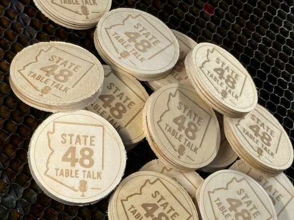 Wooden tokens with 'STATE TABLE 48' engraving on a textured surface